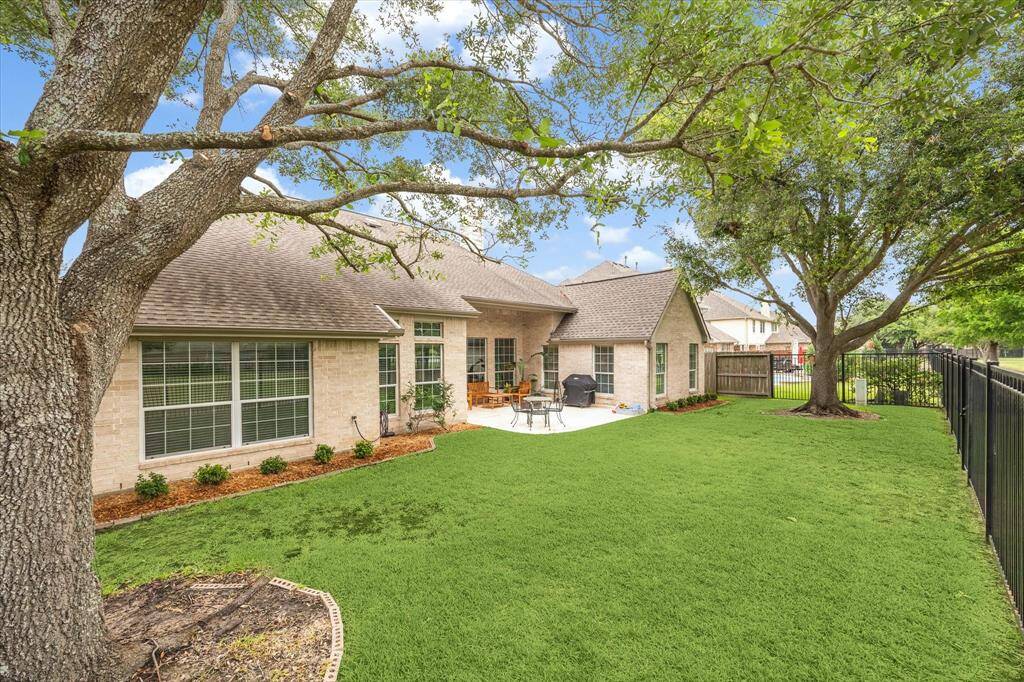 Framed by mature shade trees and backing to a scenic trail and lake, this beautifully landscaped backyard offers plenty of space to relax, play, or garden with a full sprinkler system to keep this lawn looking its best.