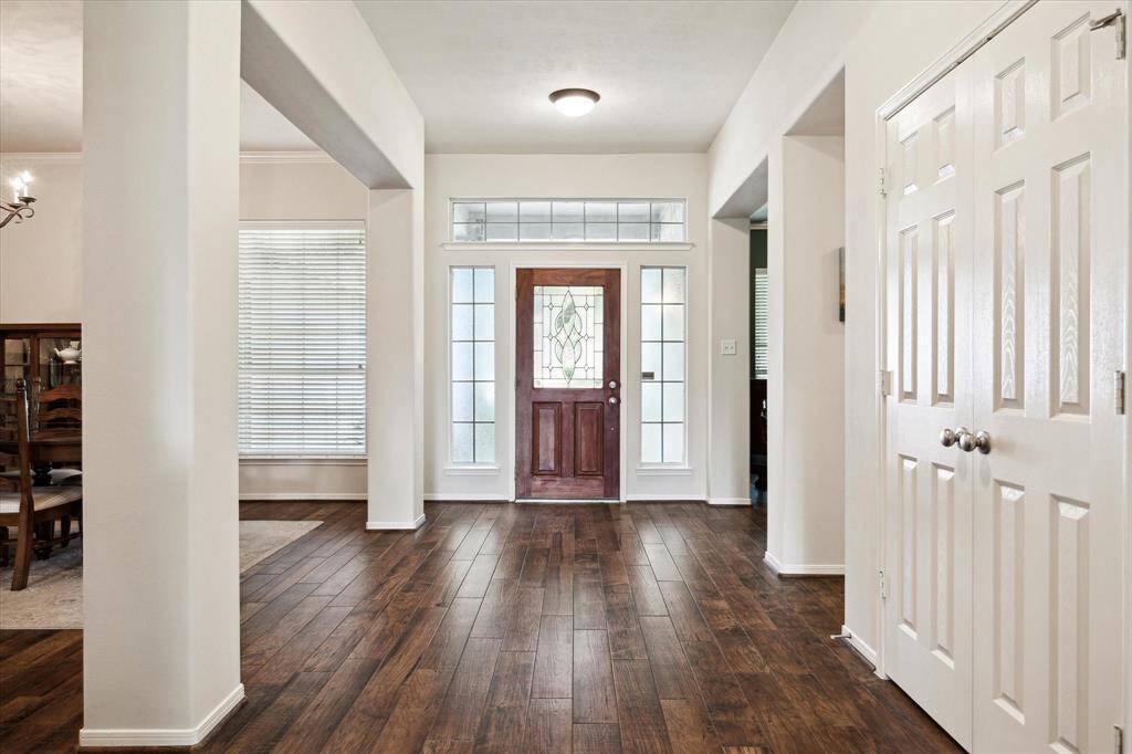 A stunning leaded glass front door with transom and sidelights sets the tone for this elegant entryway. Gorgeous wood-look tile flooring and soft natural light create a warm, welcoming first impression the moment you step inside.
