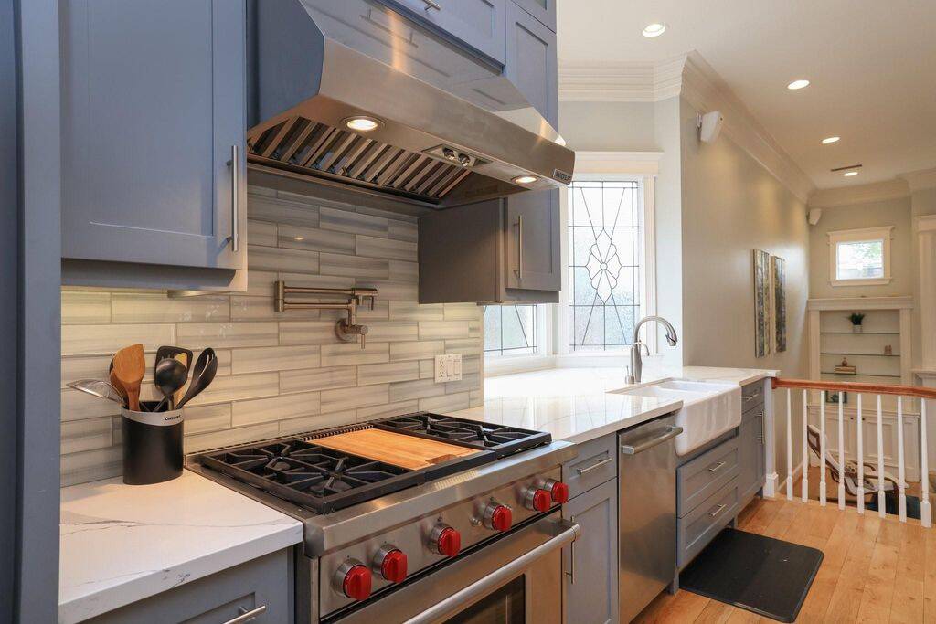 Close up of the Wolf gas range with hood and pot filler, under cabinet lighting.