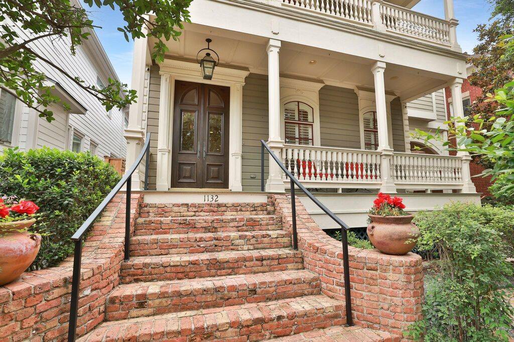 New Orleans style home has brick steps leading up to the porch with double doors and a gas lantern.