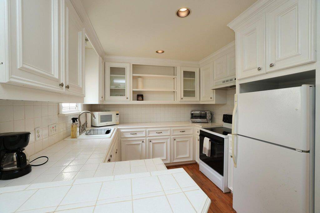 Full kitchen with a window, 2 barstools, and a table and chairs.