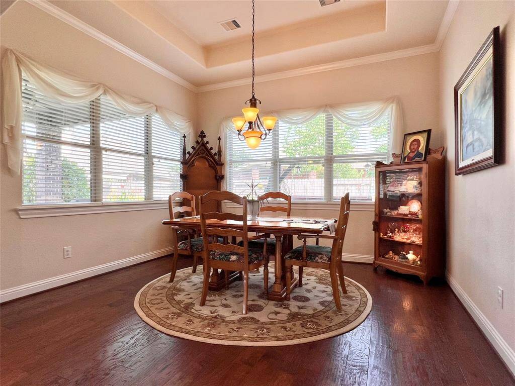 DINING ROOM WITH GOERGEOUS WOOD FLOORS, TRAYED CEILING, CHANDELIER, CROWN MOULDING, AND VAST WINDOWS.  OPTIONALLY THIS ROOM COULD ALSO WORK AS A NICE SUNROOM SPACE.