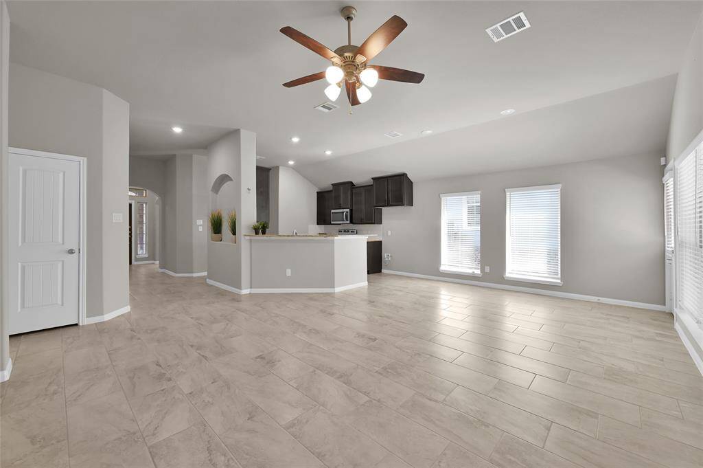 Spacious Living Room open to kitchen has cool ceramic tile throughout, high ceilings and modern LED lighting