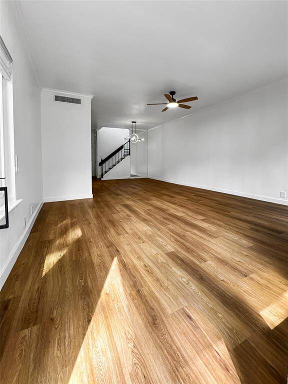 Bright and inviting living room with LVP floors, a modern ceiling fan, and a central fireplace. Large windows provide plenty of natural light, and the white walls create a clean, spacious feel.