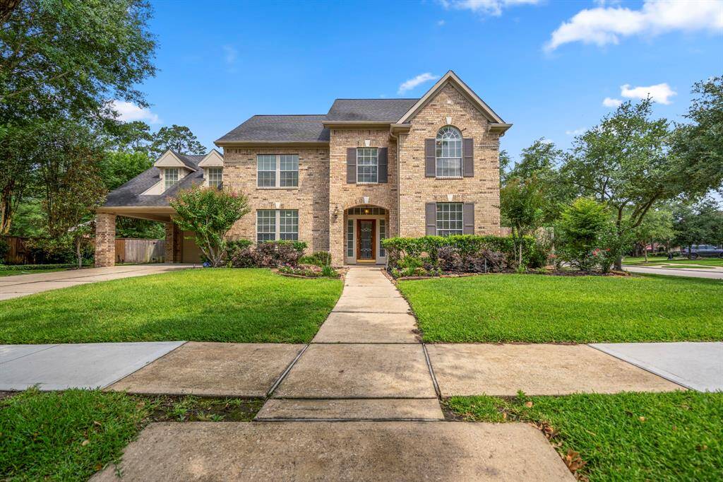 Twilight exterior of a charming brick home featuring lush landscaping, warm glow from exterior lights, and a mature tree that beautifully enhances the front yard.