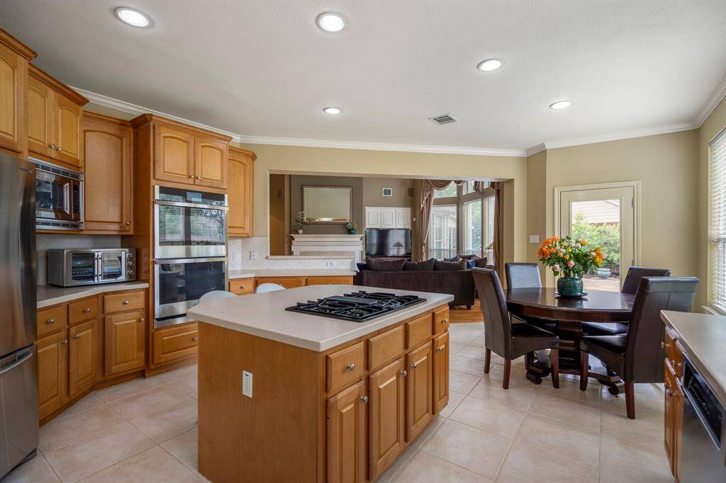 Bright and airy kitchen with a generous island for seating, plenty of natural light from large windows, and contemporary stainless steel appliances.