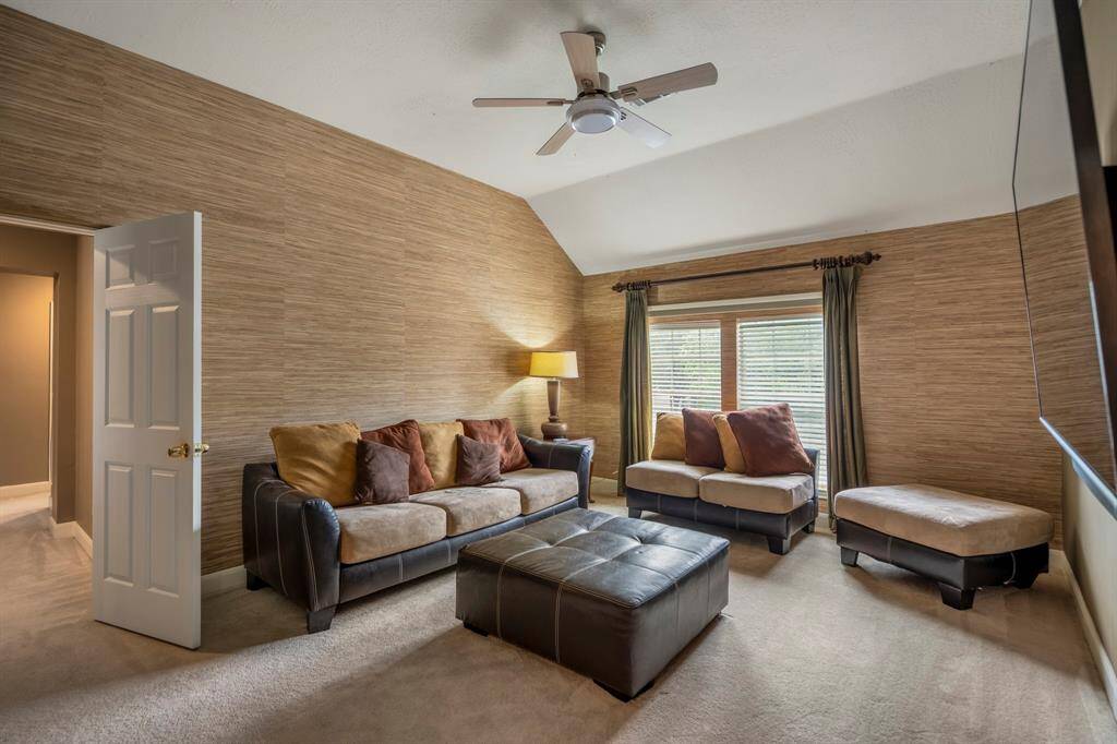 Spacious living room boasting high ceilings and large windows that flood the space with natural light. Highlights include a cozy fireplace, elegant drapery, and a comfortable seating area with views from the staircase—ideal for both relaxing and entertaining.