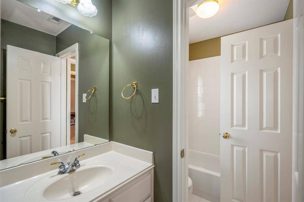 Bright and airy bathroom with a sink and mirror, illuminated by natural light streaming through the window.