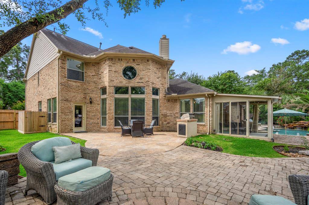 Spacious backyard with a brick exterior home that features a large patio, well-maintained landscaping, and a luxurious pool area.