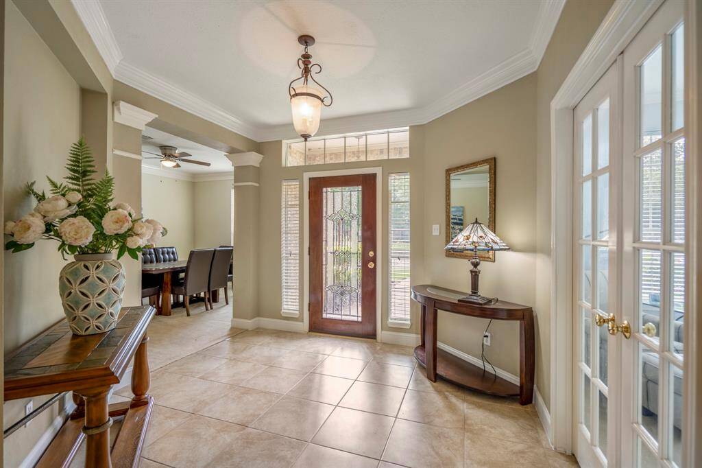 Backyard oasis with a stunning landscaped pool and waterfall, surrounded by lush greenery and palm trees. Stone patio offers shaded seating and ample space for relaxation and outdoor entertaining.