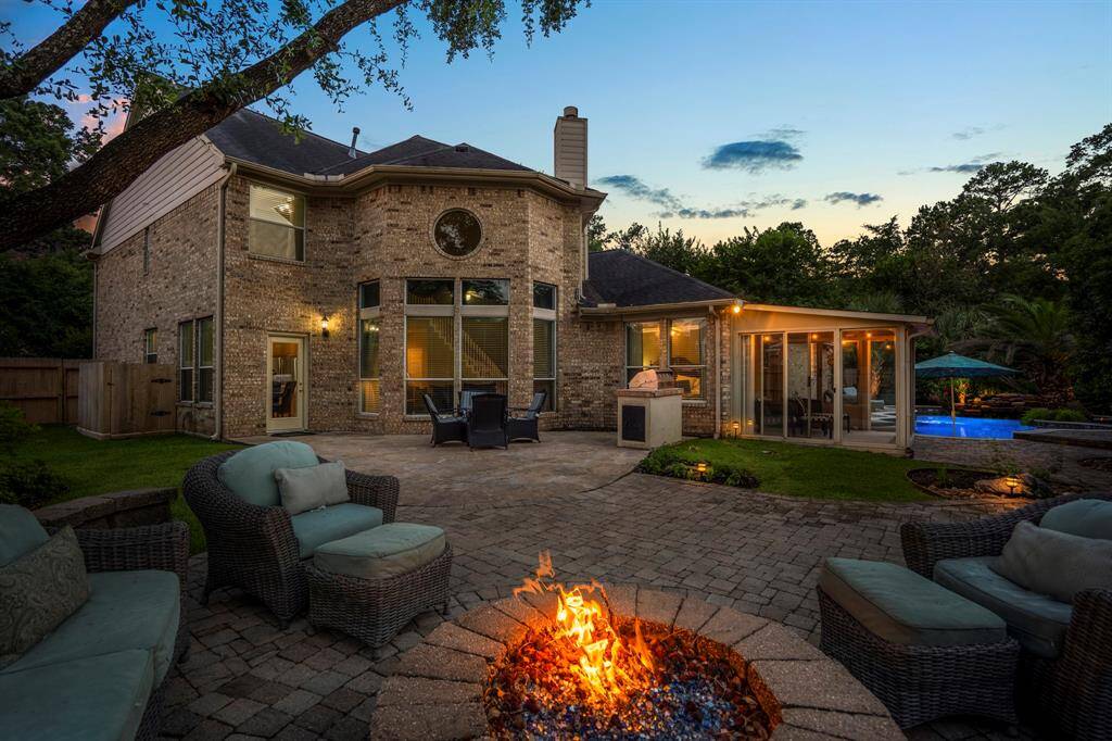 Spacious backyard is beautifully illuminated by exterior lights and a glowing fire pit. Featuring a large patio, meticulously maintained landscaping, and a stunning pool area, it’s perfect for relaxing and entertaining.