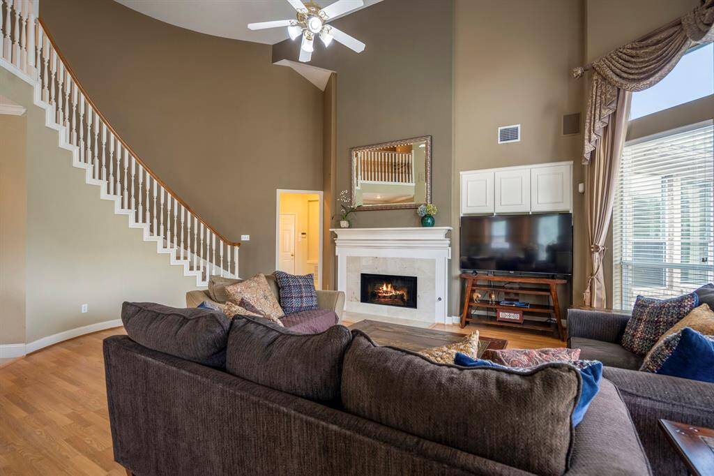 Spacious living room featuring a fireplace, soaring high ceilings, and large windows that flood the space with natural light.