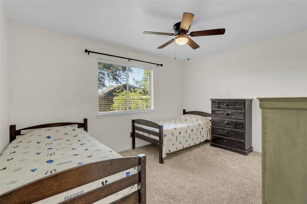 Charming Bedroom: Bright and cozy space featuring plush carpeting, a ceiling fan for comfort, and a serene view from the window.