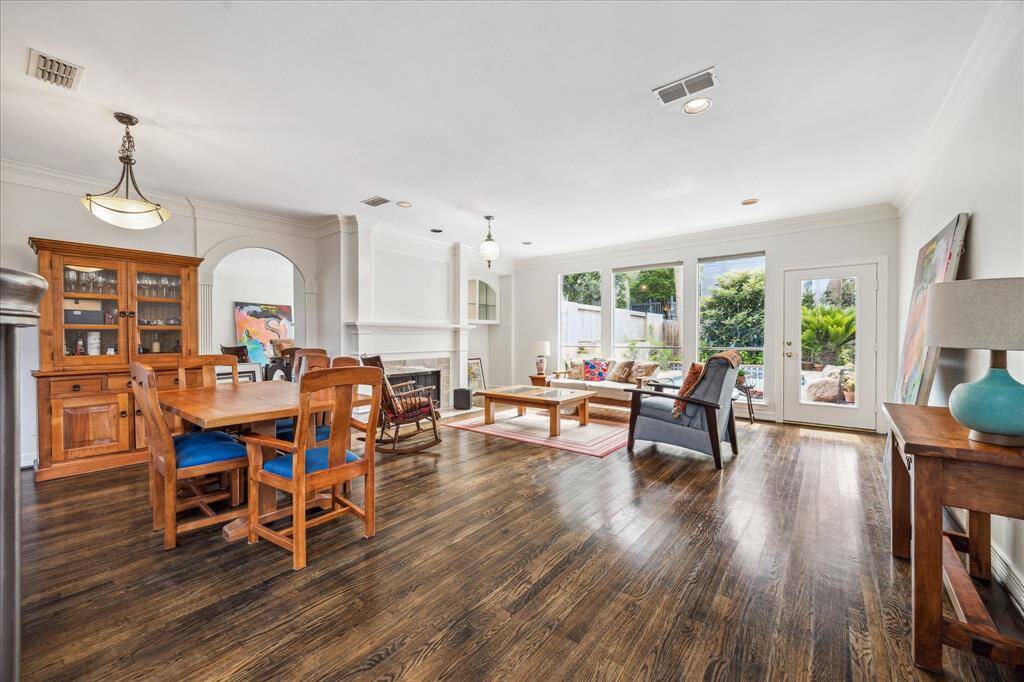 Step into a bright living and dining area featuring rich wood floors and a stunning pool view.