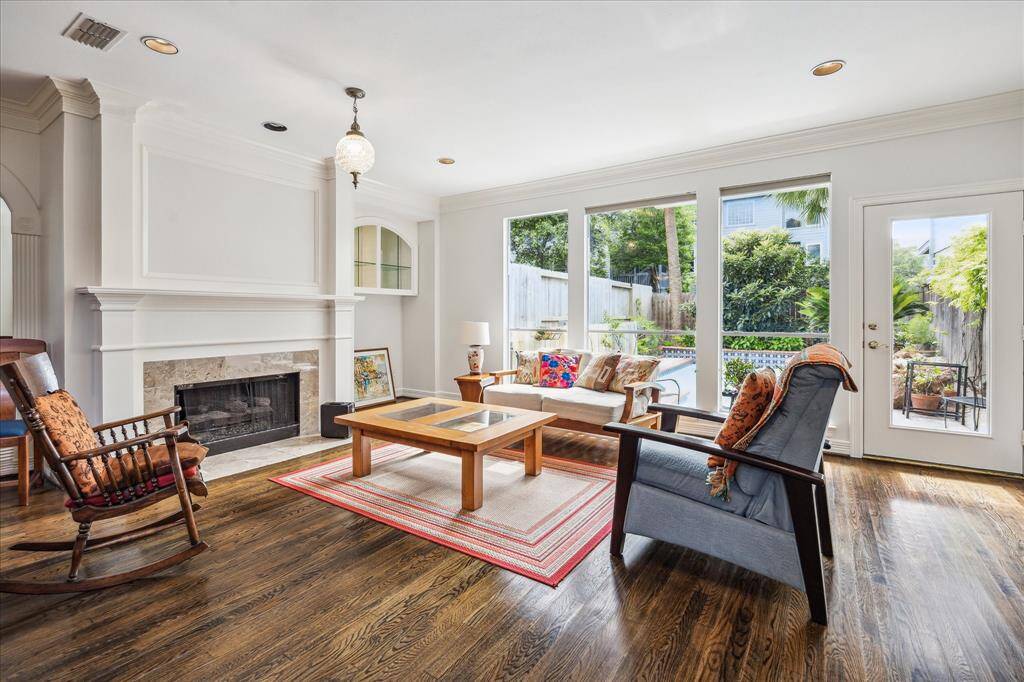 Spacious living room featuring a cozy fireplace, soaring ceilings, elegant crown moldings, and gleaming hardwood floors.
