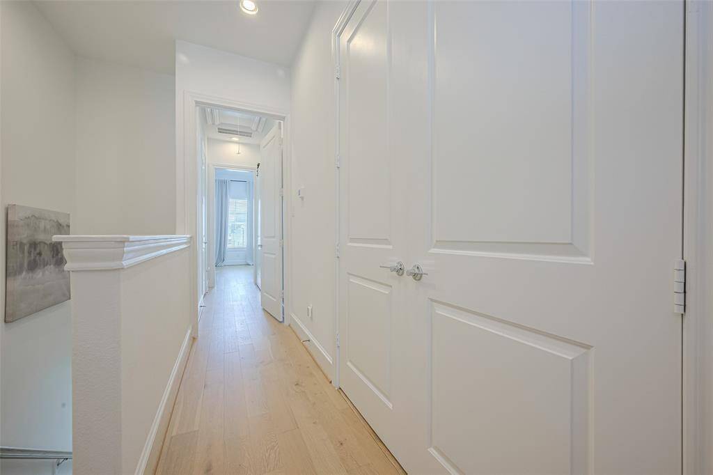 At the top of the stairs, this hallway houses the laundry closet -- inside the set of double doors. Ahead at the end of the hall is the lovely primary suite.