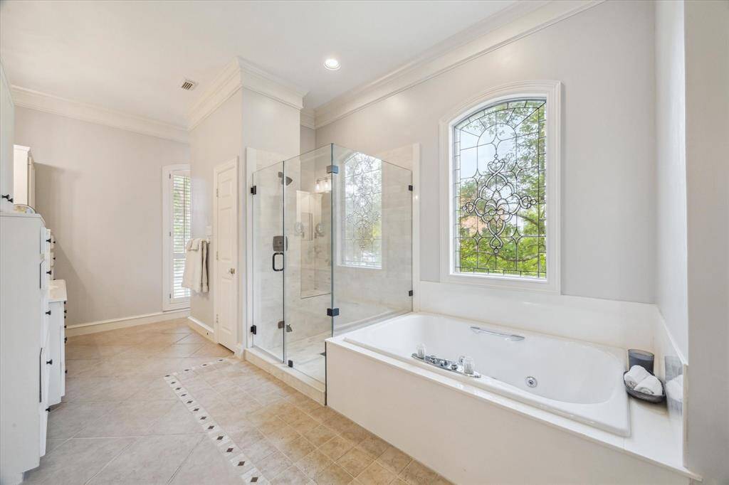 Primary bathroom with recently remodeled shower, large jetted soaking tub, and beautiful glass window.
