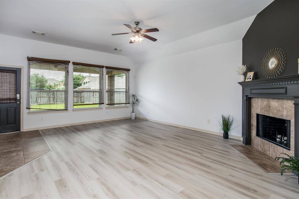 Cozy and full of charm, this living room features new flooring, a warm fireplace, abundant natural light, and a welcoming layout perfect for relaxing or entertaining.