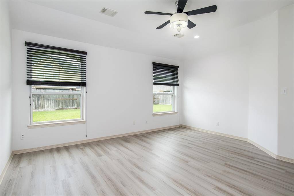 The spacious primary bedroom features large windows overlooking the garden, filling the room with natural light and offering a peaceful, scenic view.