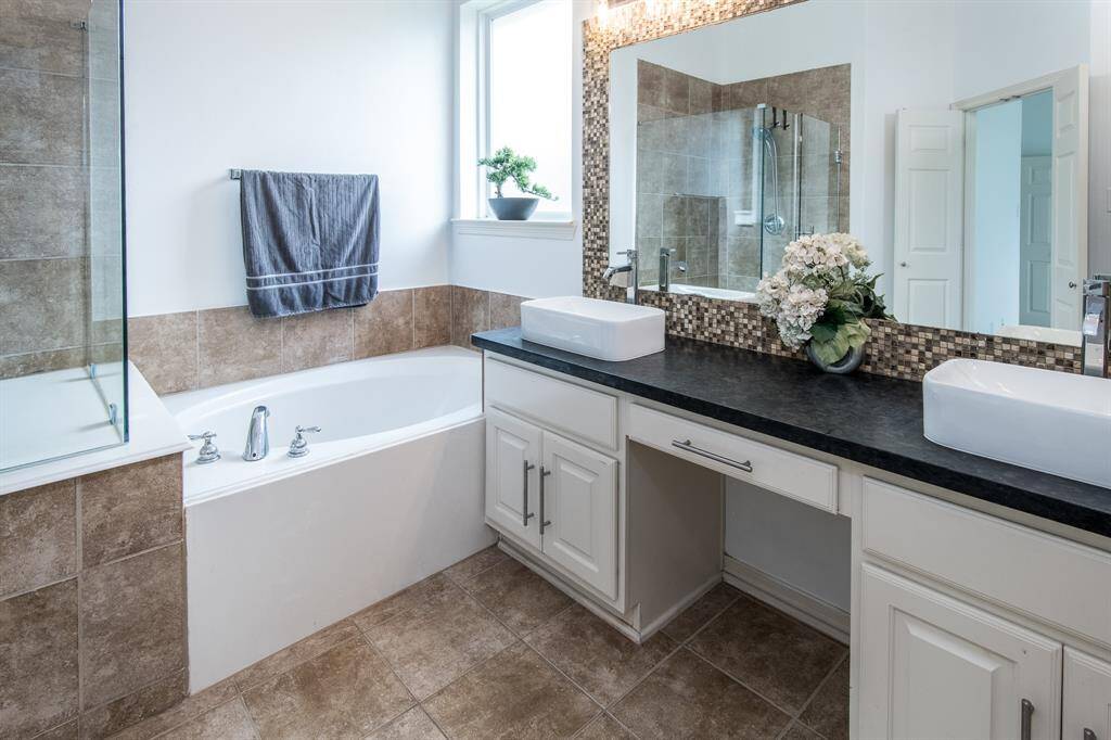The primary bathroom boasts a stylish design with his and hers sinks, providing ample space and convenience for two.
