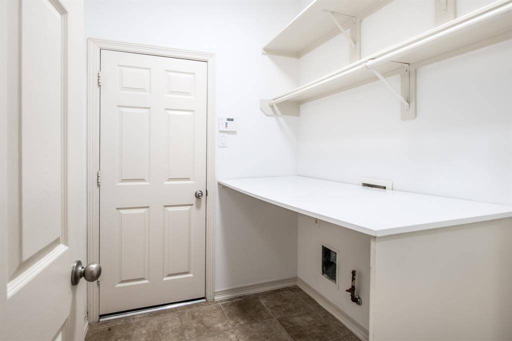 This compact laundry room is efficiently designed with a convenient folding counter and built-in shelves, providing ample space for organization and storage.