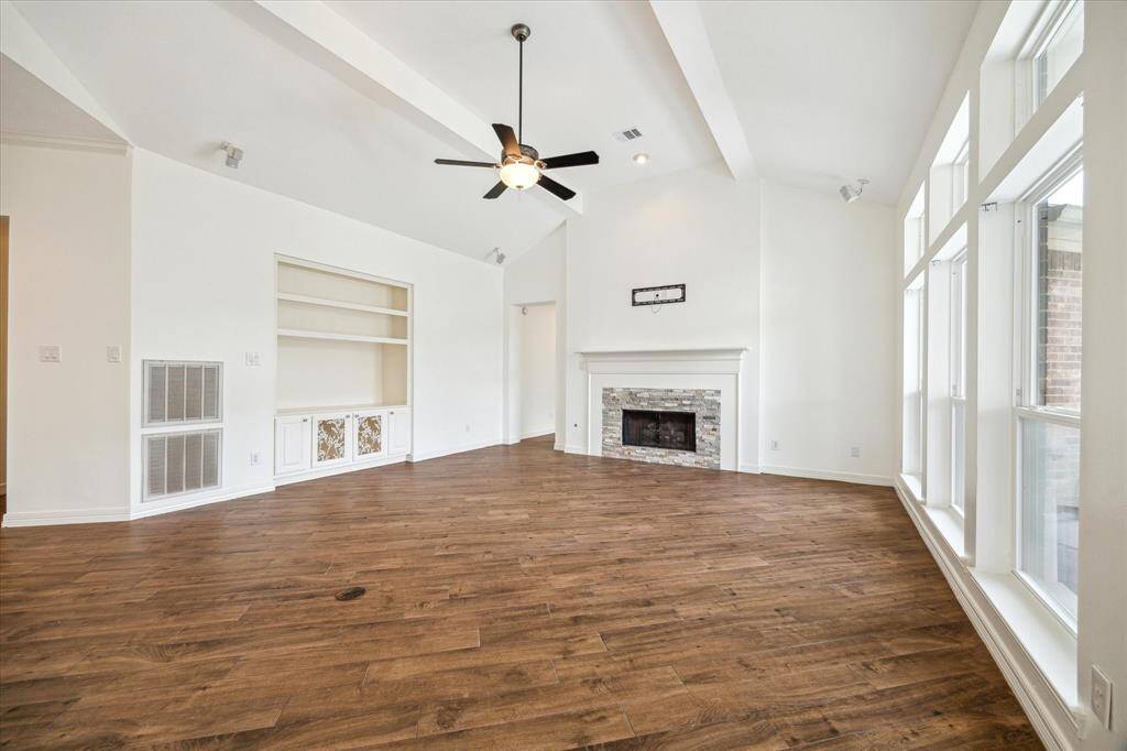 The Living Room is flooded with natural light through a wall of windows, features a fireplace & built in's.