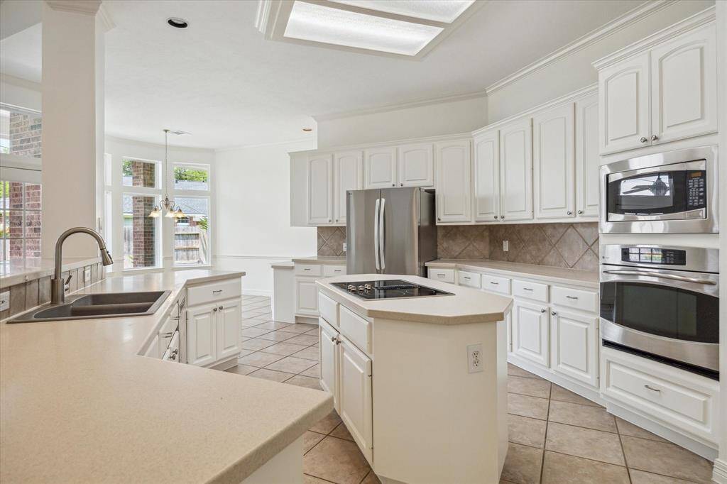 The chef's Kitchen has corian countertops, a large island, stainless steel appliances and ample cabinet space! Fridge STAYS!