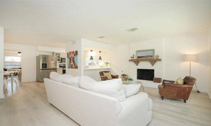 Living Room & Kitchen ViewOpen living area with painted brick fireplace and sightlines to kitchen.