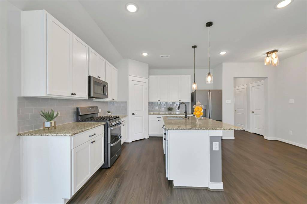 Lovely kitchen with subway tile backsplash, island, and pendant lighting. Double oven range.