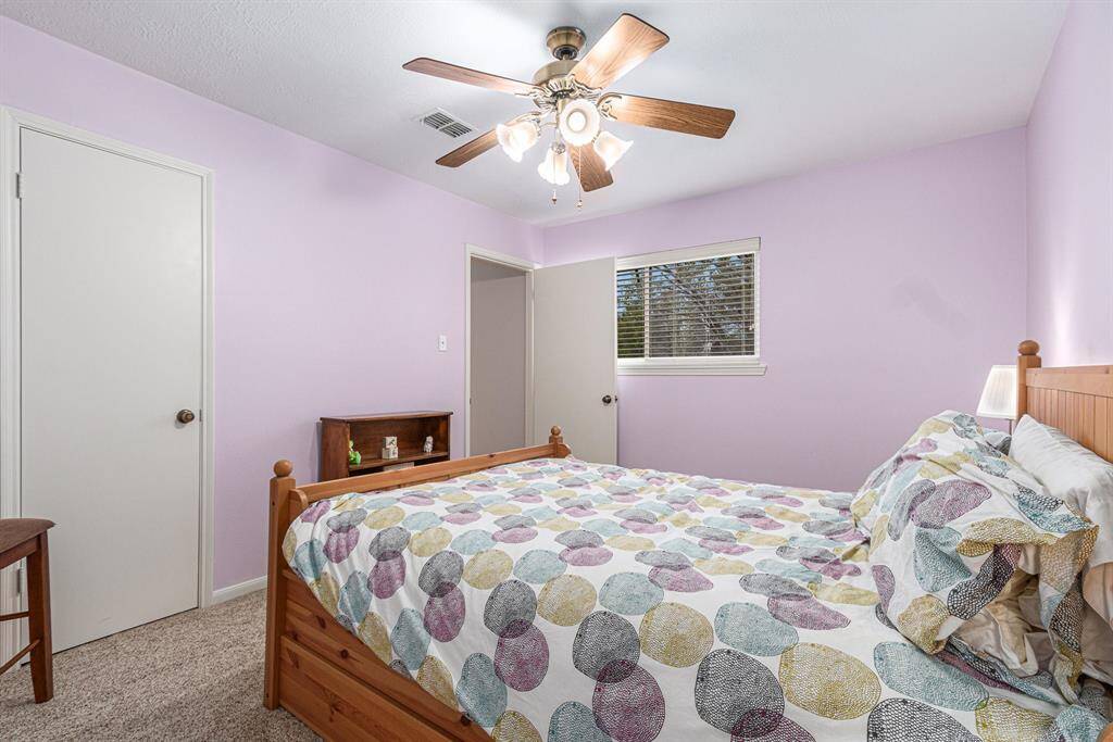 The third secondary bedroom with neutral carpet, soft paint color and ceiling fan.