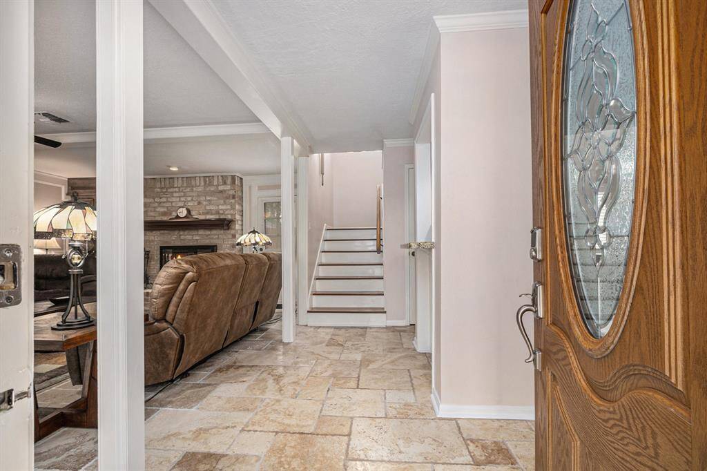 Enter through a wood and glass front door onto travertine flooring and spacious living area.