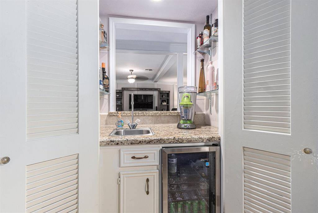 Wet bar is accessible from the living area and the dining room. Louvered doors can be closed from the dining room. Entertaining is easy with the beverage refrigerator and glass shelving for your barware.