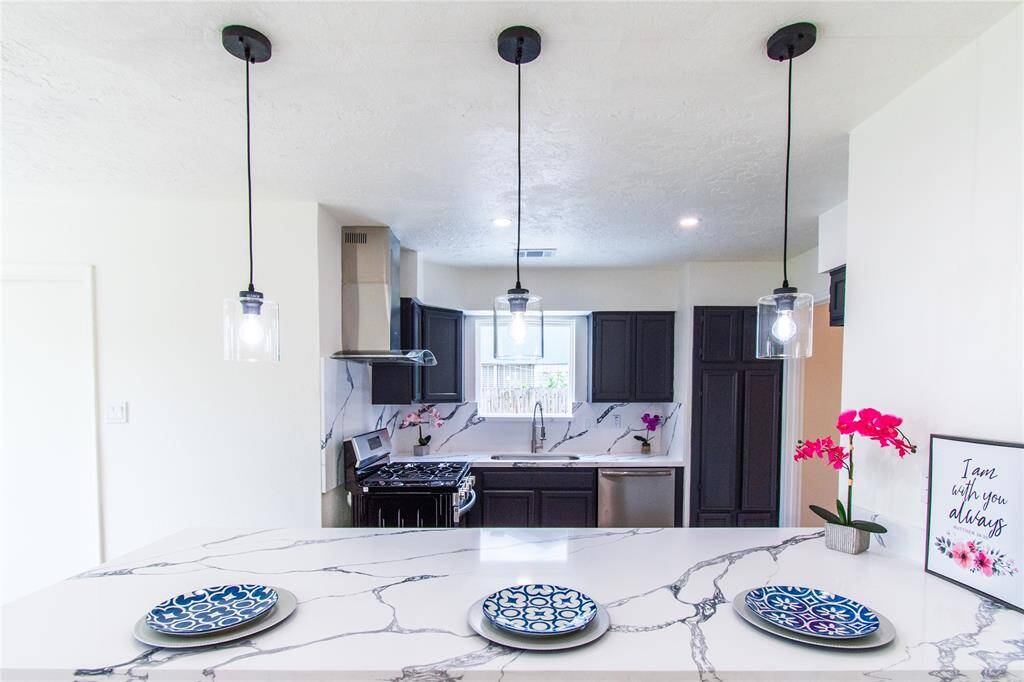 Elegant pendant lights illuminate the modern kitchen, enhancing its stylish design.