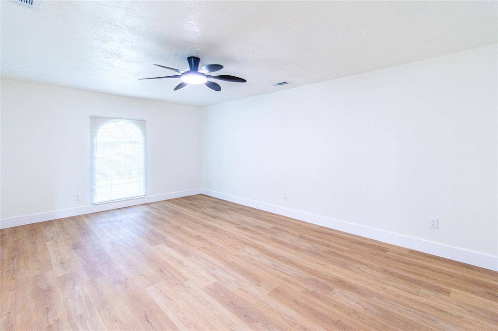 Primary bedroom featuring elegant vinyl floors, abundant natural light, and a modern ceiling fan for ultimate comfort.