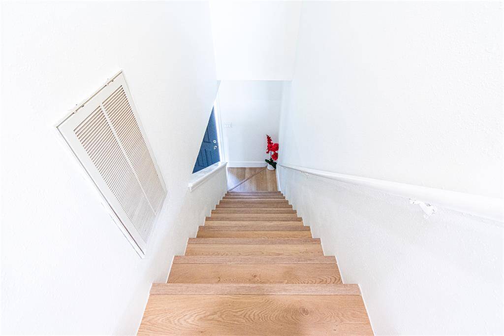 Bright and inviting staircase leading to the lower level, featuring elegant wood steps and a sleek handrail. Perfect for a modern touch.