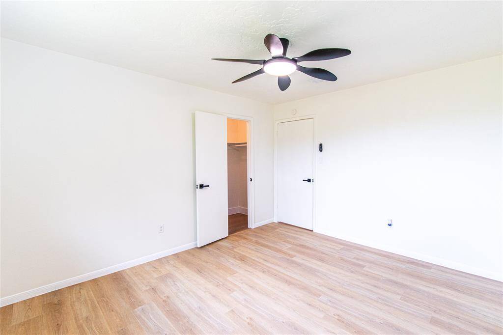 Bedroom 2 featuring sleek hardwood floors, ample closet space, and a modern ceiling fan. Perfect for comfort and style.