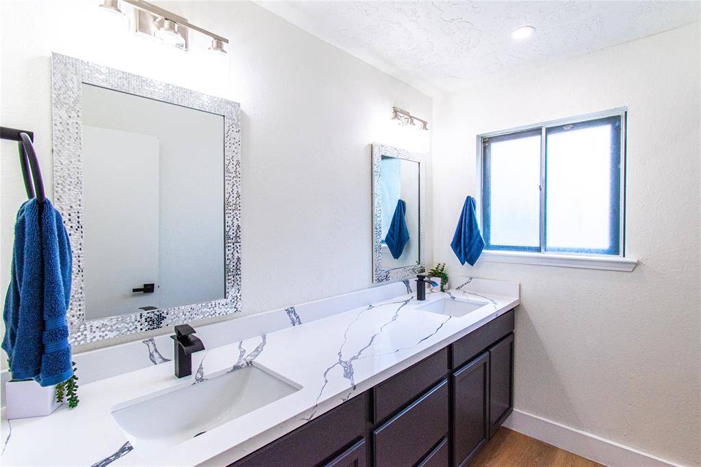 Second bathroom featuring double sinks, elegant fixtures, and natural light. Perfect for family or guests.