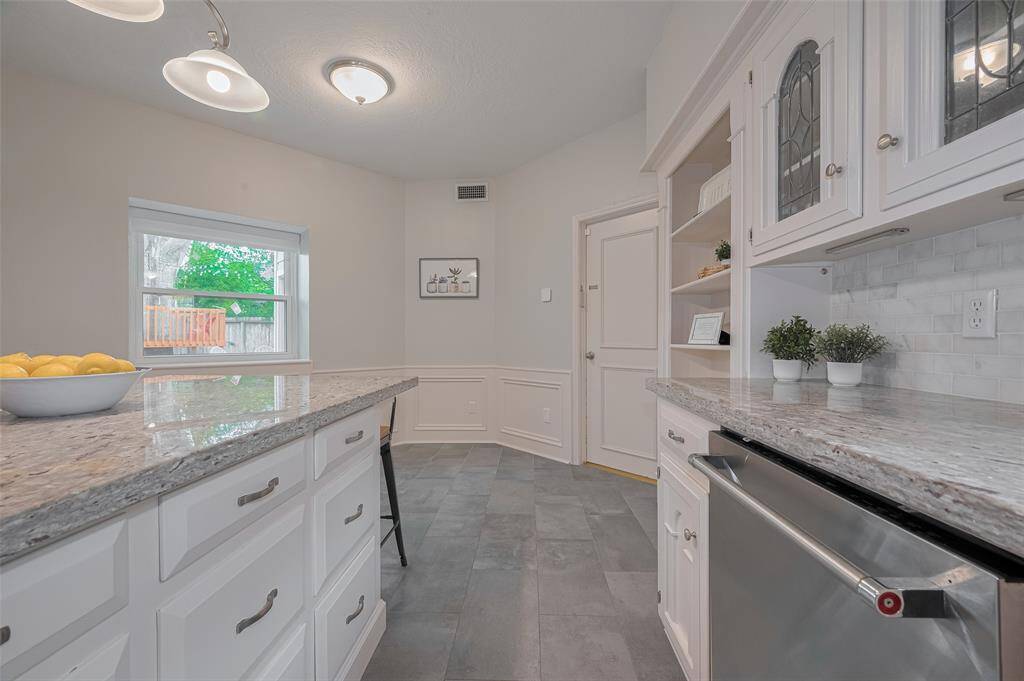 Charming leaded glass upper cabinets add a touch of elegance and character to the kitchen. Just beyond, there’s a cozy space perfectly suited for a breakfast table and chairs—ideal for casual dining or morning coffee.