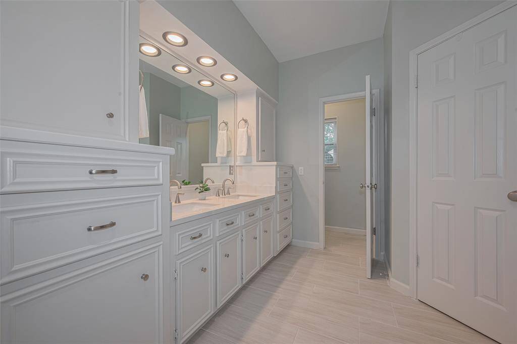 The expansive vanity features dual sinks, recessed lighting, and a built-in mirror. With abundant drawers and cabinetry, there's plenty of storage for all your essentials. The commode is thoughtfully tucked away for added privacy.