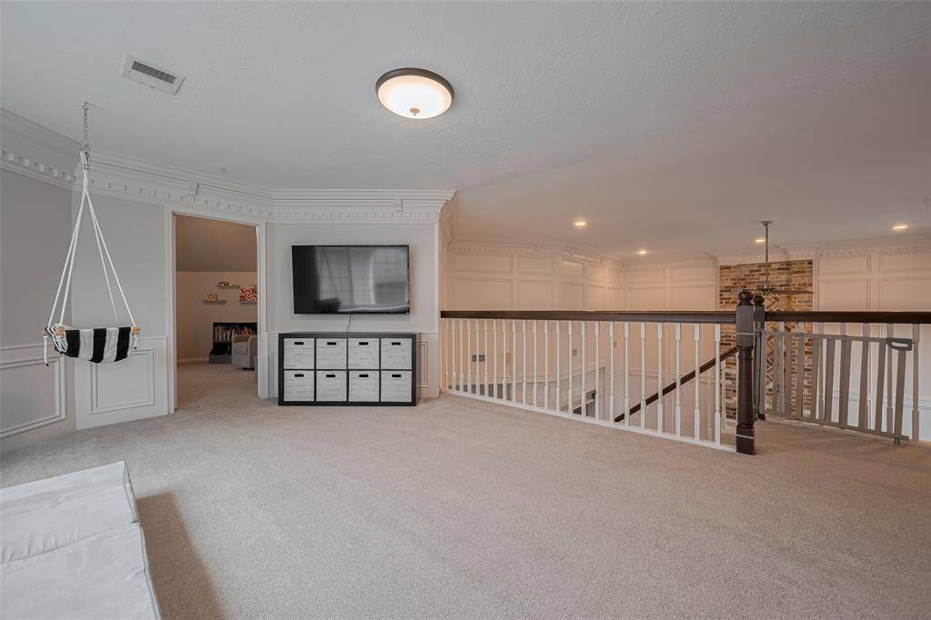 Plush carpeting underfoot adds warmth and comfort to this expansive game room, providing ample space for a large sectional, chairs, a pool table, and more.