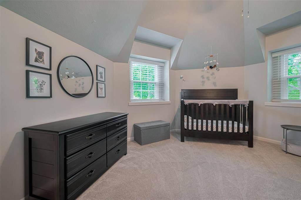 Guest bedroom one features plush carpeting, soft decorator paint, and charming windows that bathe the room in abundant natural light—creating a warm and inviting retreat for visitors.