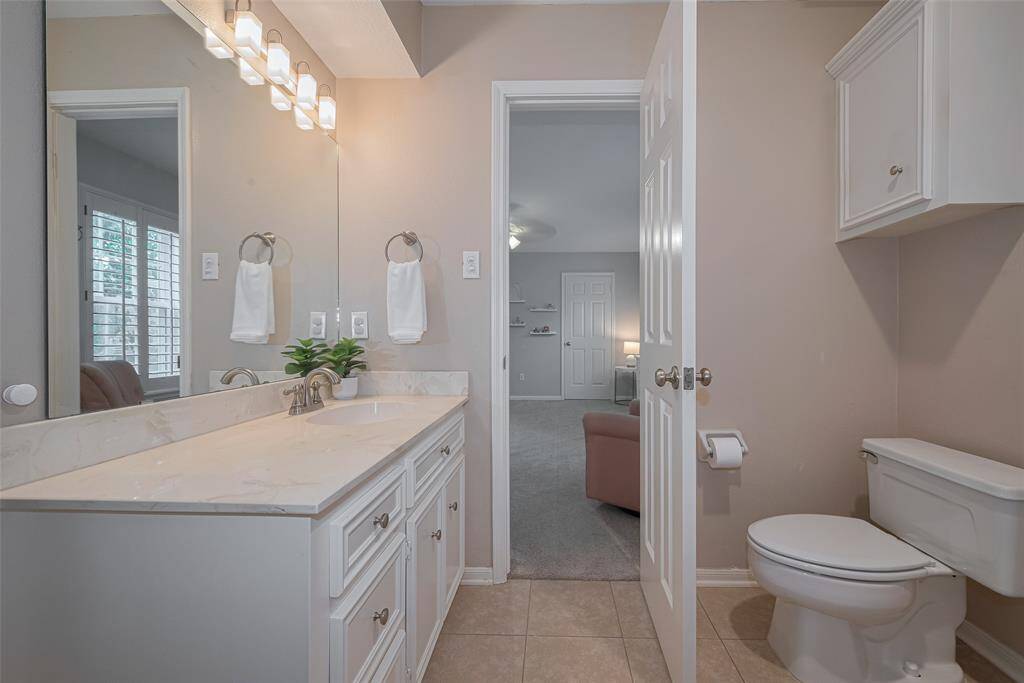 An alternate perspective highlights the second vanity, showcasing sleek countertops, a modern lighting fixture, and neutral tile flooring.