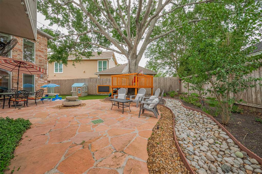 The backyard boasts layered dimension and texture, featuring a flagstone patio bordered by pea gravel, transitioning to larger rock accents, and finished with a mulch bed—creating a visually appealing and thoughtfully designed outdoor space.