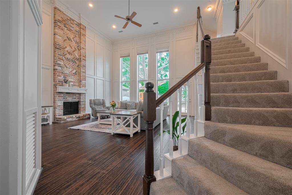 Continue into the impressive living room, where a soaring two-story ceiling, floor-to-ceiling wood paneling, and expansive windows create a sense of grandeur. A striking brick fireplace stretches to the ceiling, serving as a dramatic focal point in this captivating space.