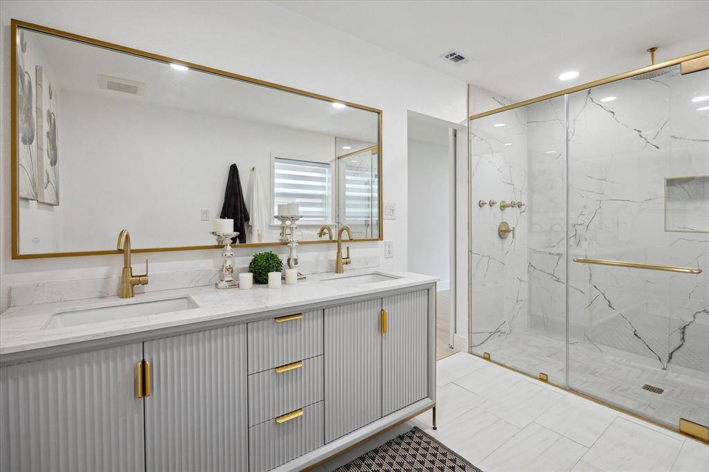 The bathroom stuns with double sinks, sleek surfaces, and striking gold finishes for a luxe look.