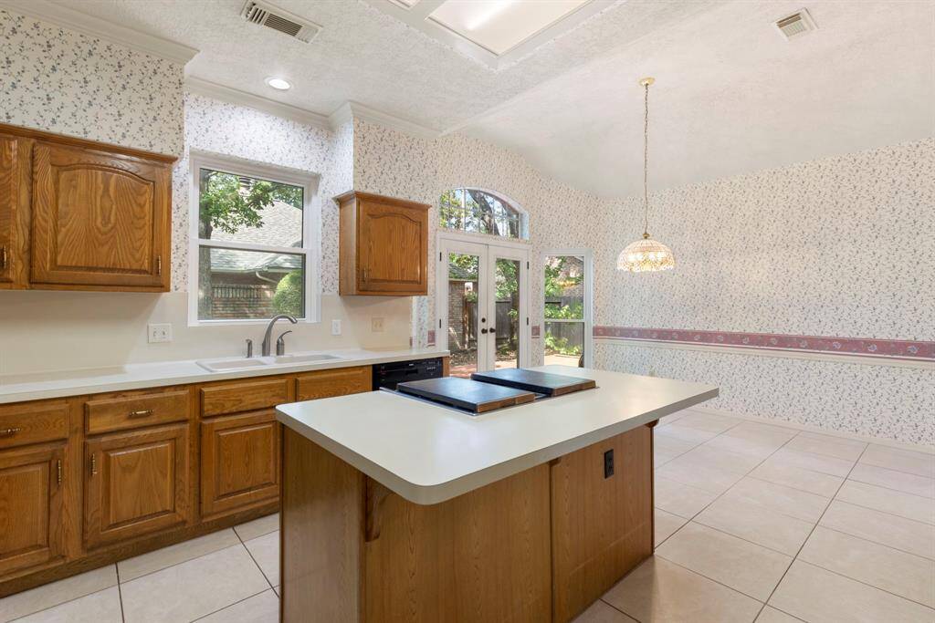 The kitchen opens to a light-filled breakfast area with double doors to the patio, creating a seamless flow between indoor and outdoor living.