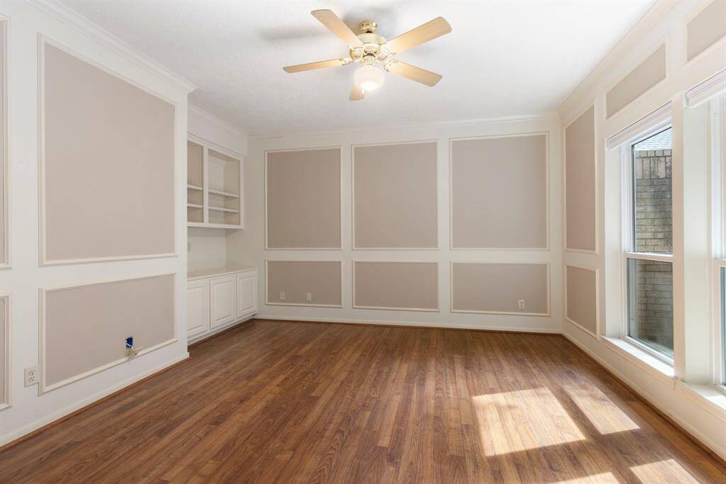 The elegant study features laminate wood flooring, custom wall paneling, built-in cabinetry, and abundant natural light.