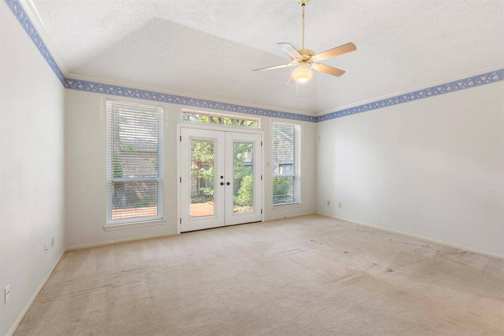 The spacious primary suite features vaulted ceilings, ample natural light, and private patio access through elegant double doors.