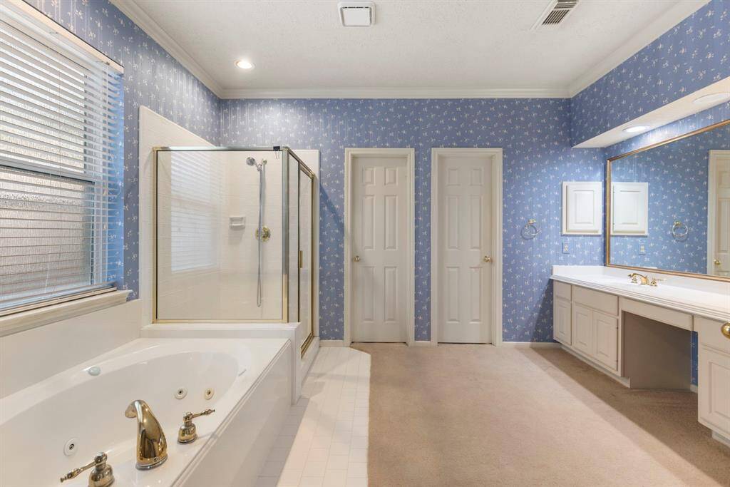 The primary bath offers a jetted tub, glass-enclosed walk-in shower, dual sinks with seated vanity area, and two separate walk-in closets.