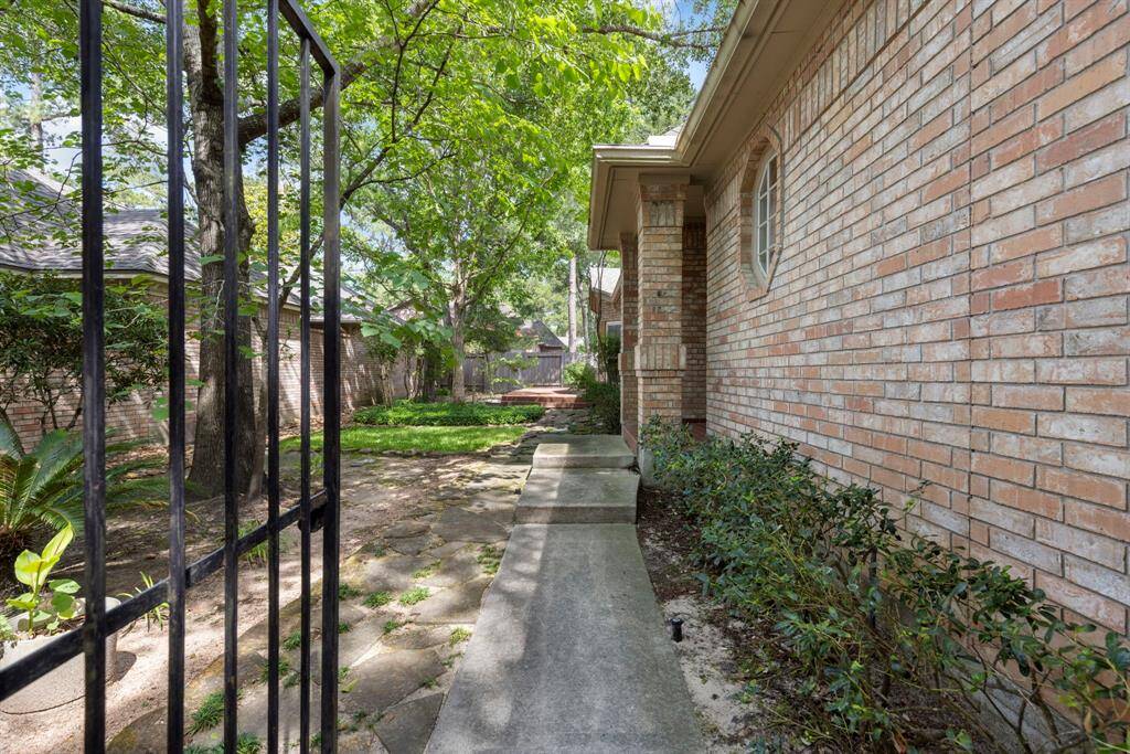 A private gated entrance welcomes you with a charming pathway leading to the front door and a secluded patio, all nestled within an enclosed yard for added privacy and tranquility.